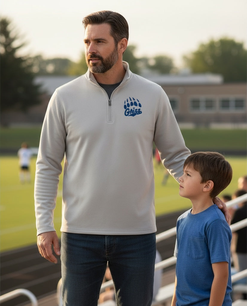 JSD Apparel men's beige midweight fleece quarter zip pullover with blue Grizzlies paw logo on a sports field.