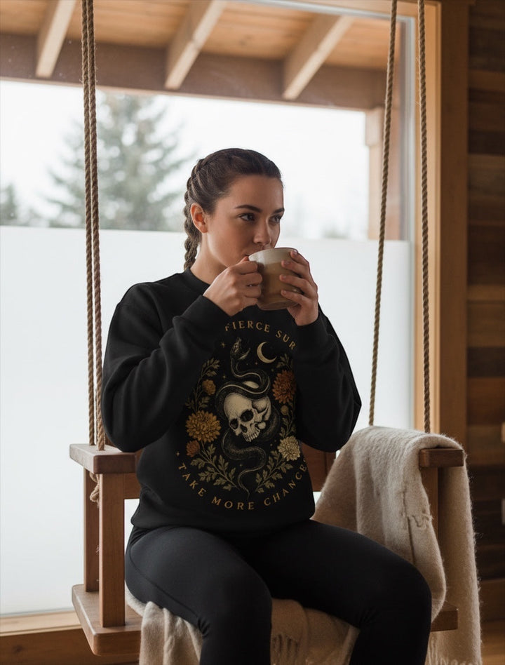 JSD Apparel black mock neck sweatshirt with skull, serpent, and floral graphic worn by a woman on a wooden swing.