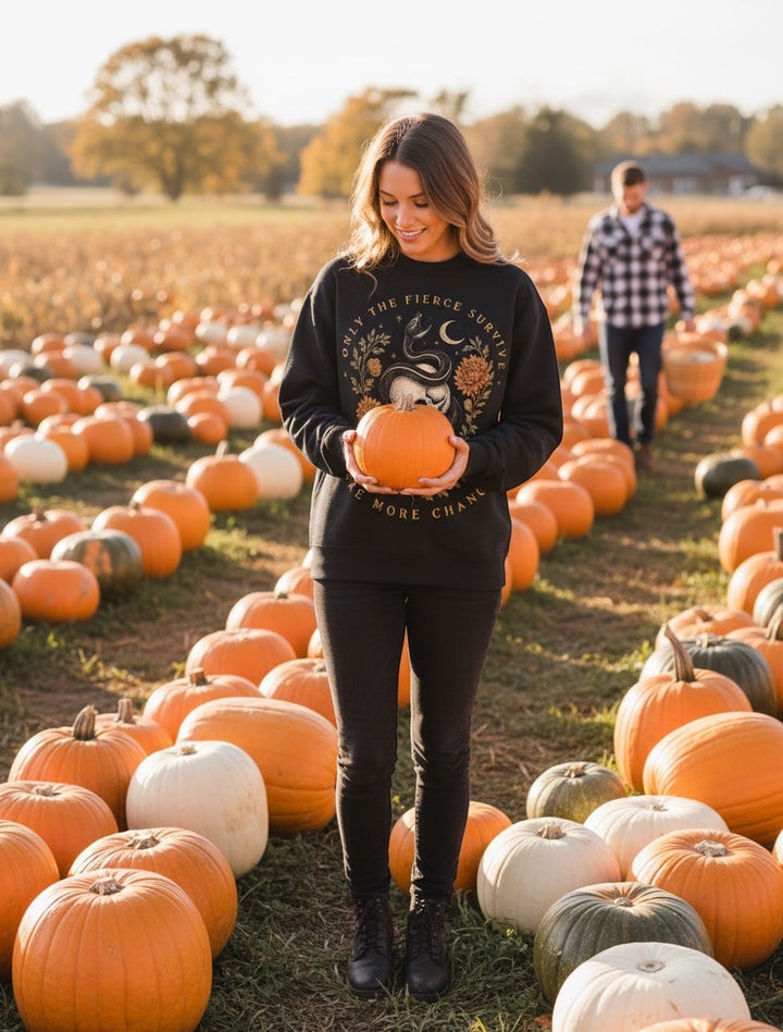 JSD Apparel black mock neck sweatshirt with skull and serpent graphic worn by a woman in a pumpkin patch.
