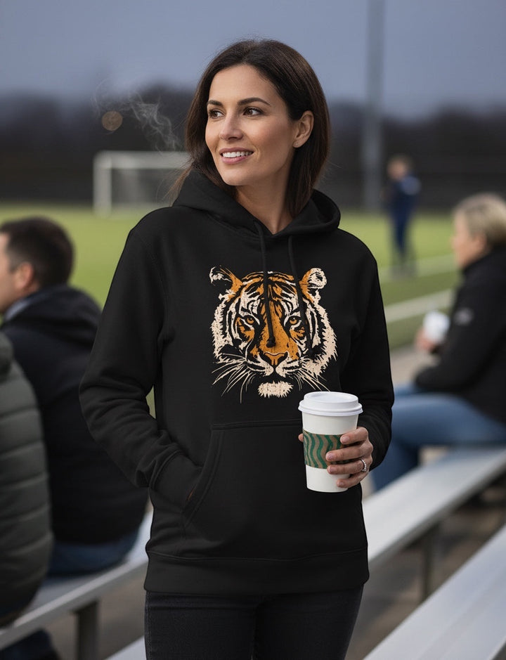 Woman wearing a JSD Apparel black heavyweight hoodie with a vintage tiger graphic while holding a coffee cup outdoors.