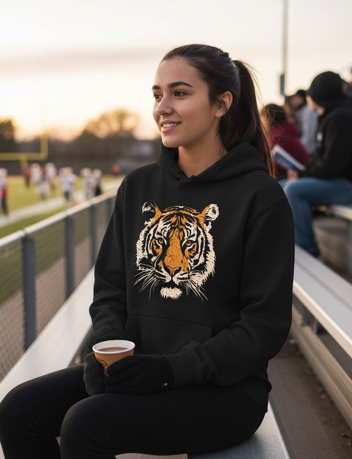 JSD Apparel Fierce Spirit black heavyweight hoodie with a vintage tiger graphic worn by a woman at a sports stadium.