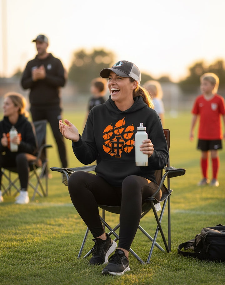 JSD Apparel black heavyweight hoodie with distressed orange Idaho Falls Tigers paw logo worn by a smiling woman