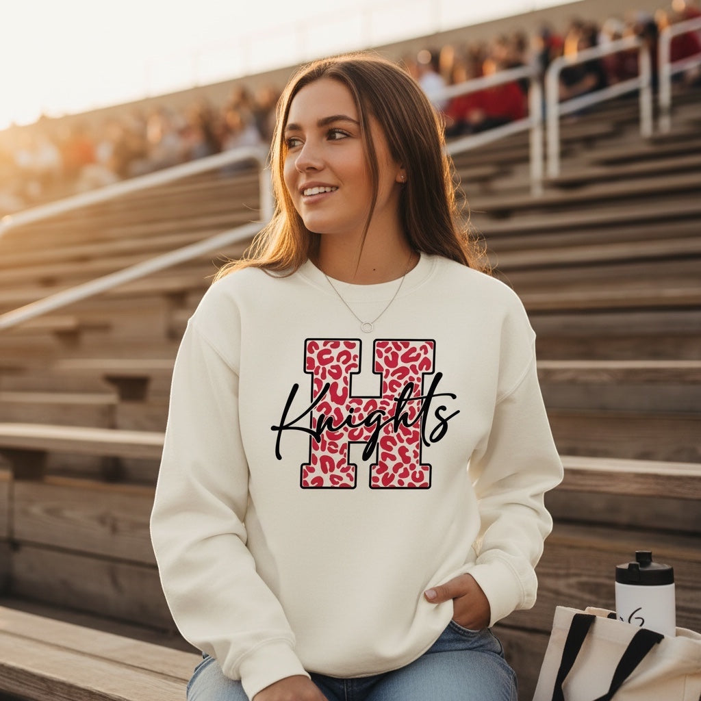 JSD Apparel cream heavyweight crewneck sweatshirt with red leopard-print H and black Knights script on a student