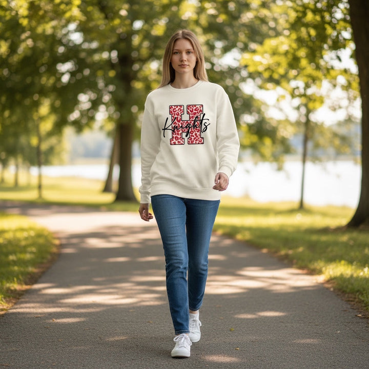 JSD Apparel cream heavyweight crewneck sweatshirt with red leopard-print H and black Knights script worn by a woman