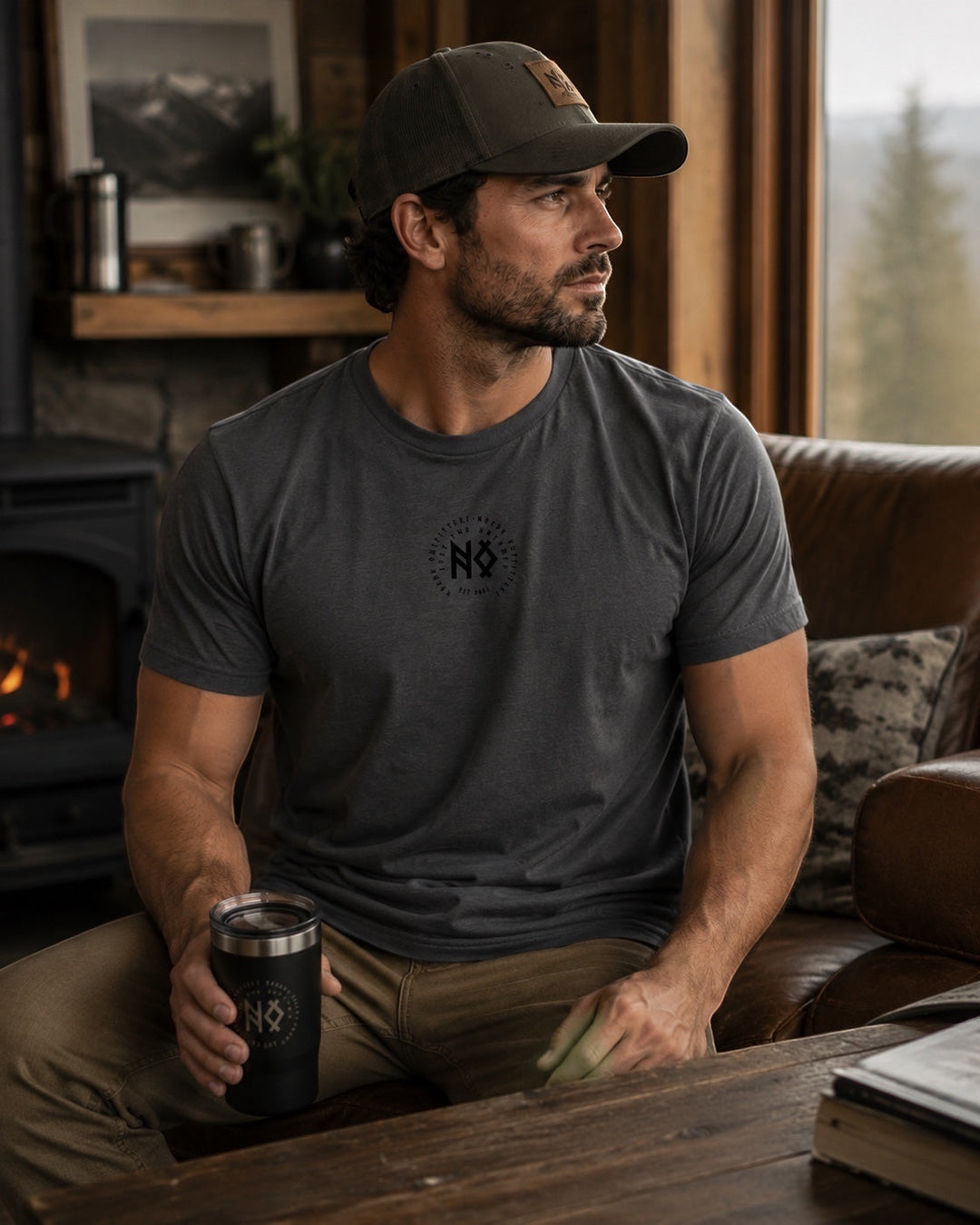 JSD Apparel dark grey short-sleeve tee with a small black chest logo and a man wearing it while holding a black tumbler.