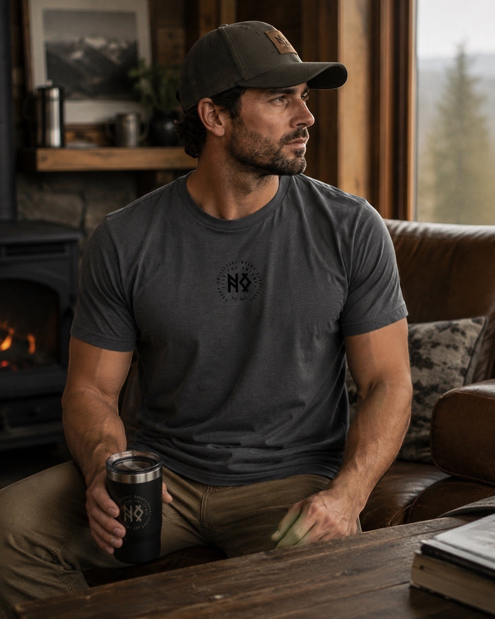 JSD Apparel dark grey short-sleeve tee with a small black chest logo and a man wearing it while holding a black tumbler.