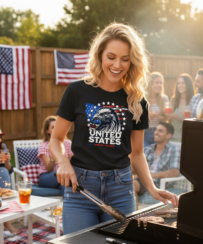 Woman wearing JSD Apparel black Land of The Free Eagle tee with patriotic flag graphic at a backyard barbecue.