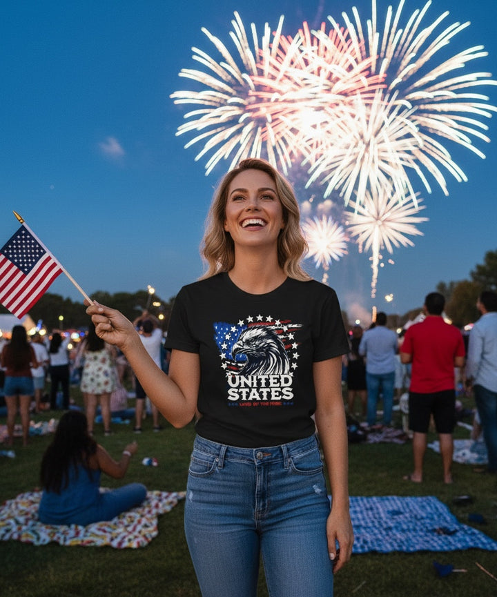 Woman wearing JSD Apparel black Land of The Free Eagle tee with American flag graphic at a fireworks celebration.