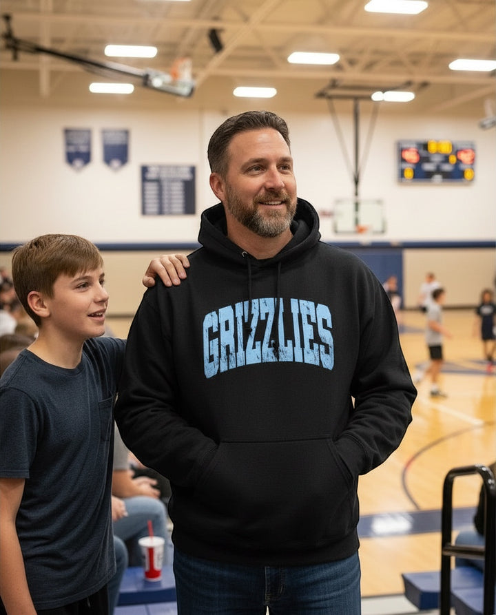 JSD Apparel Skyline Grizzlies Arch Hoodie in black with distressed blue lettering worn by a man in a gym.