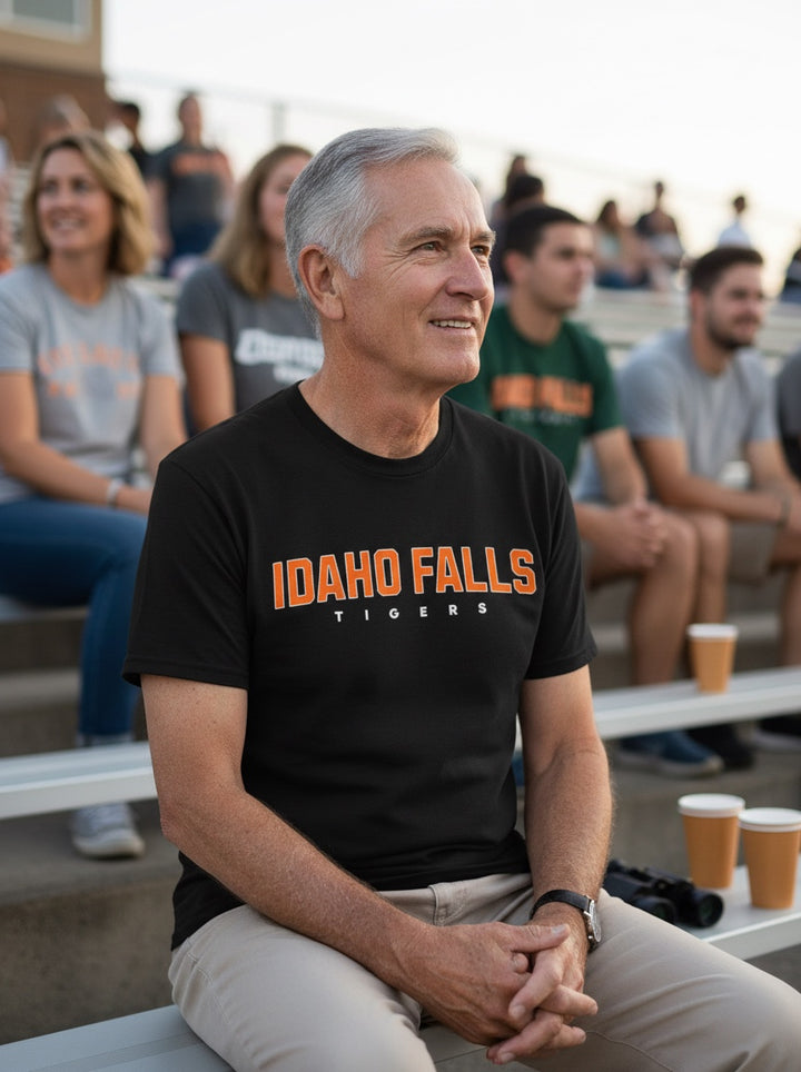 JSD Apparel Idaho Falls Tigers black cotton student tee worn by a man at a stadium game