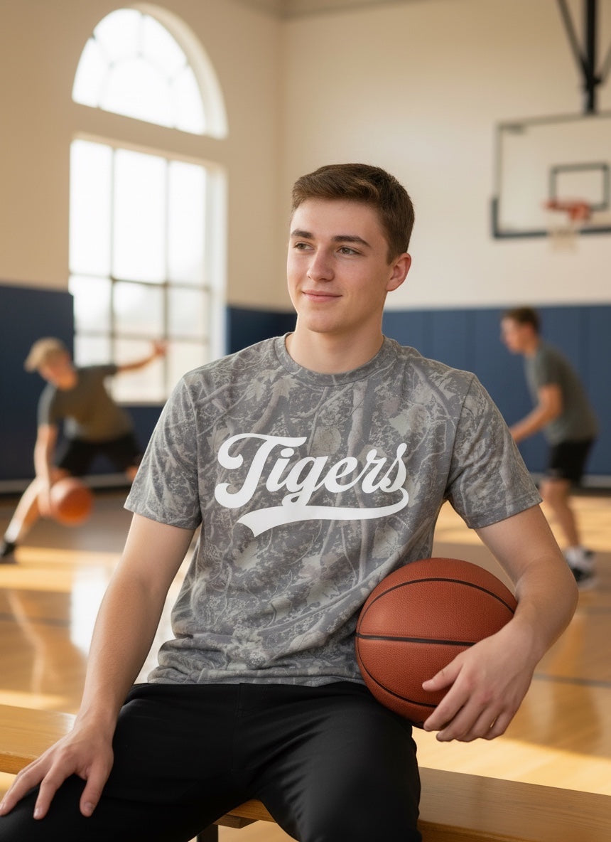 JSD Apparel Idaho Falls Tigers premium cotton tee in grey camo with white script, worn by a student in a gym.