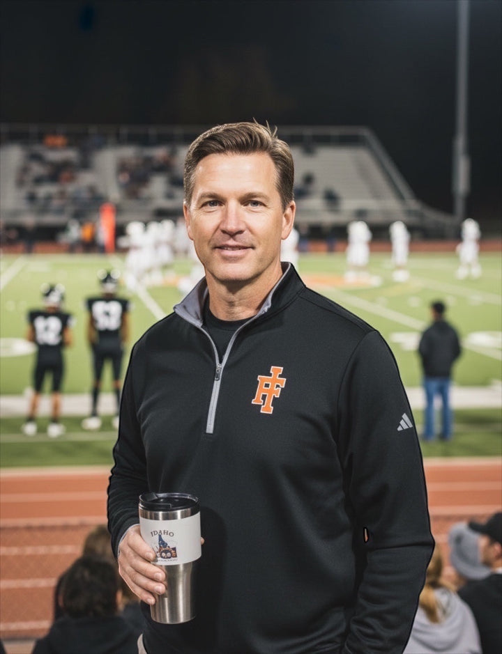 JSD Apparel Idaho Falls Tigers Adidas black quarter-zip pullover worn by a man on a football field at night