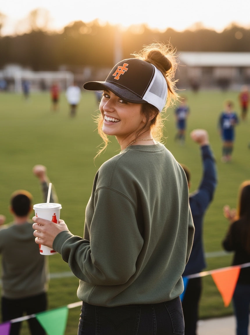 Woman wearing a JSD Apparel Idaho Falls Tigers Richardson 112 black and white trucker hat at a sports field.