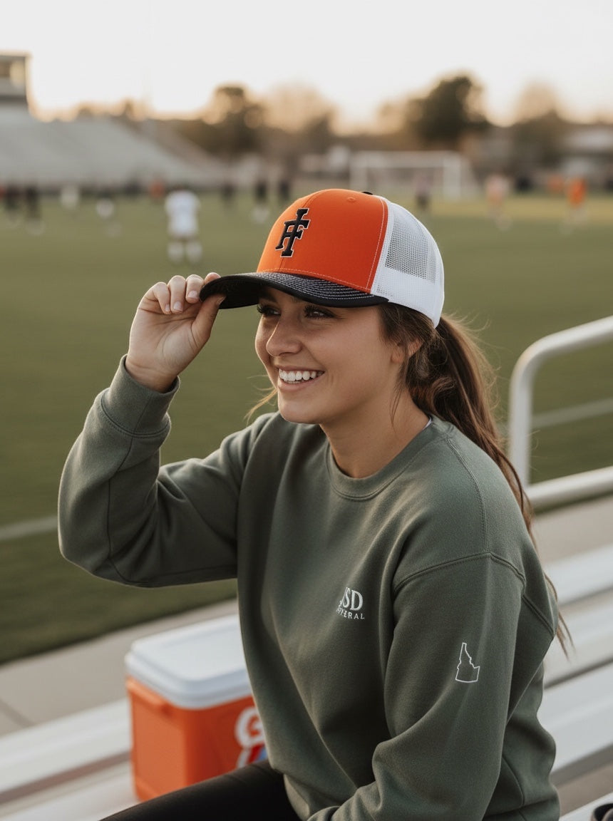 A woman wearing a JSD Apparel Idaho Falls Tigers Richardson 112 snapback hat with orange front and white mesh back.