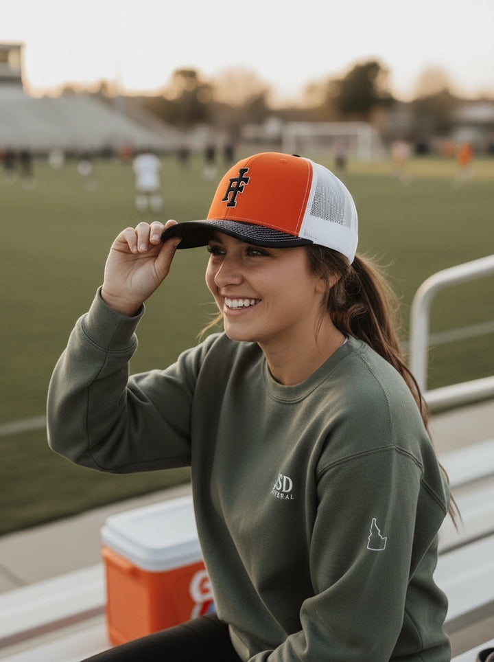 A woman wearing a JSD Apparel Idaho Falls Tigers Richardson 112 snapback hat with orange front and white mesh back.
