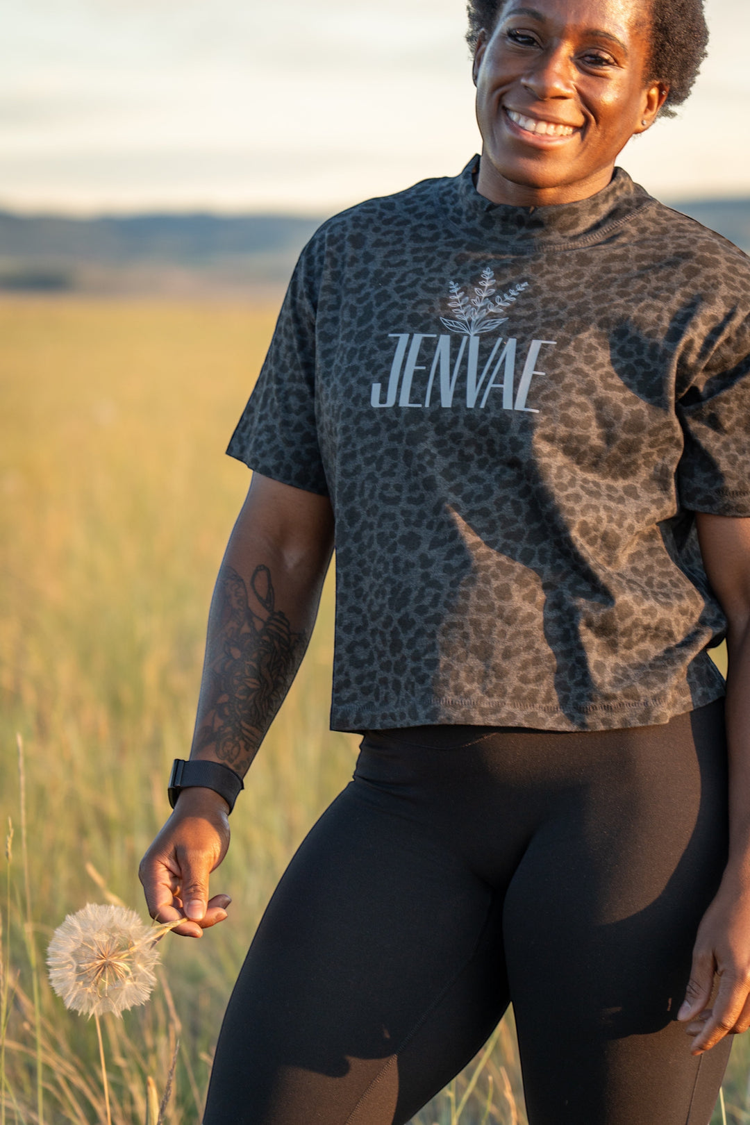 JSD Apparel Jenvae boxy cropped t-shirt in shadow black leopard print with sage branch logo, worn in a field.