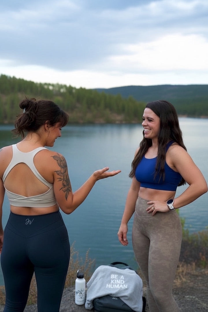 Two women wearing JSD Apparel Jenvae leggings and sports bras outdoors by a lake, showcasing high-waisted fit.