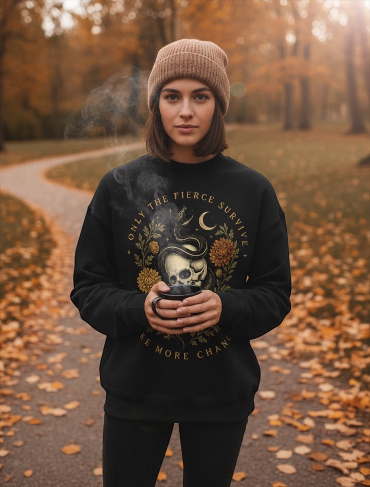 JSD Apparel mock neck sweatshirt with skull and serpent graphic worn by a woman in a beanie in an autumn park.
