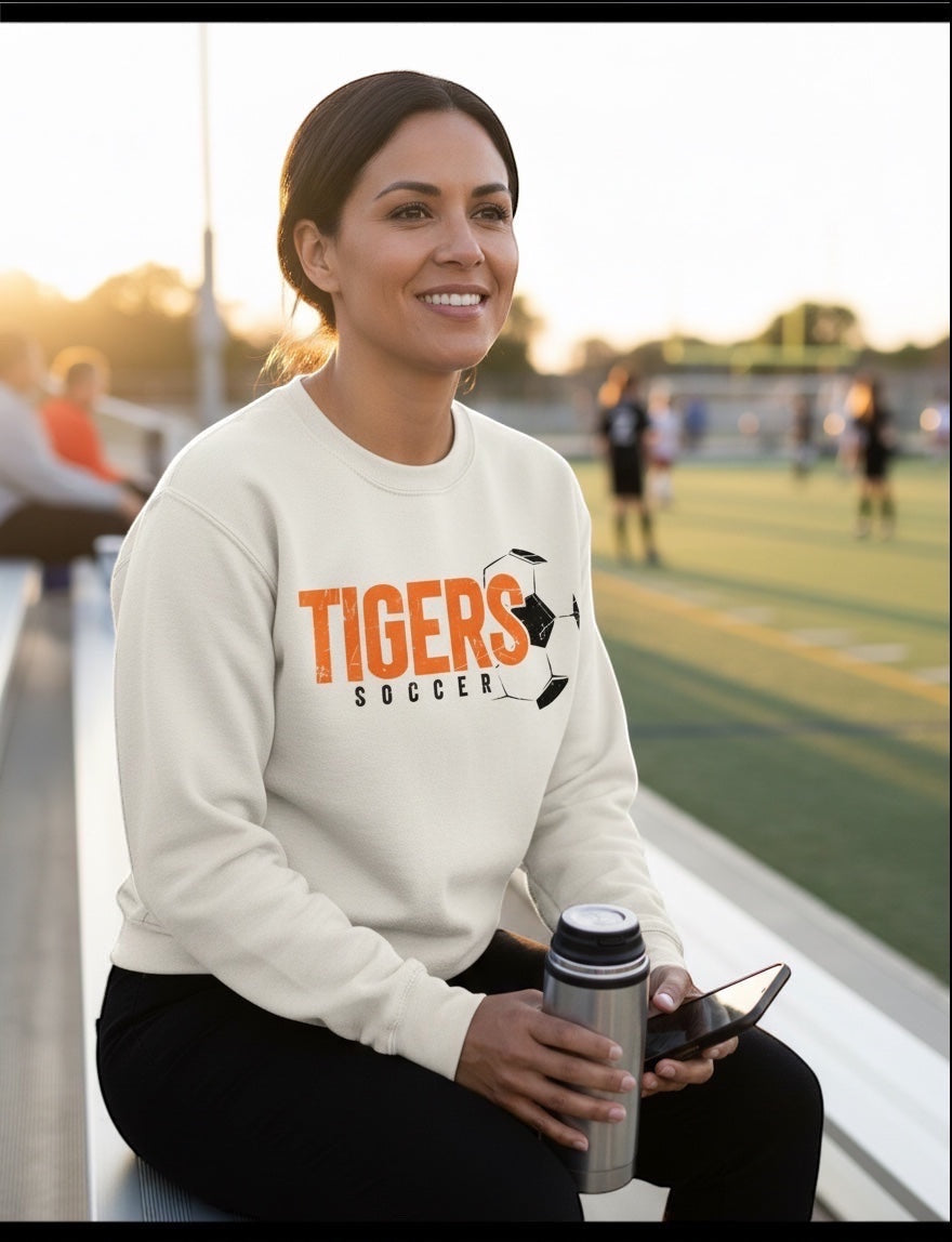 JSD Apparel natural crewneck sweatshirt with distressed orange and black Tigers Soccer graphic worn by a smiling woman