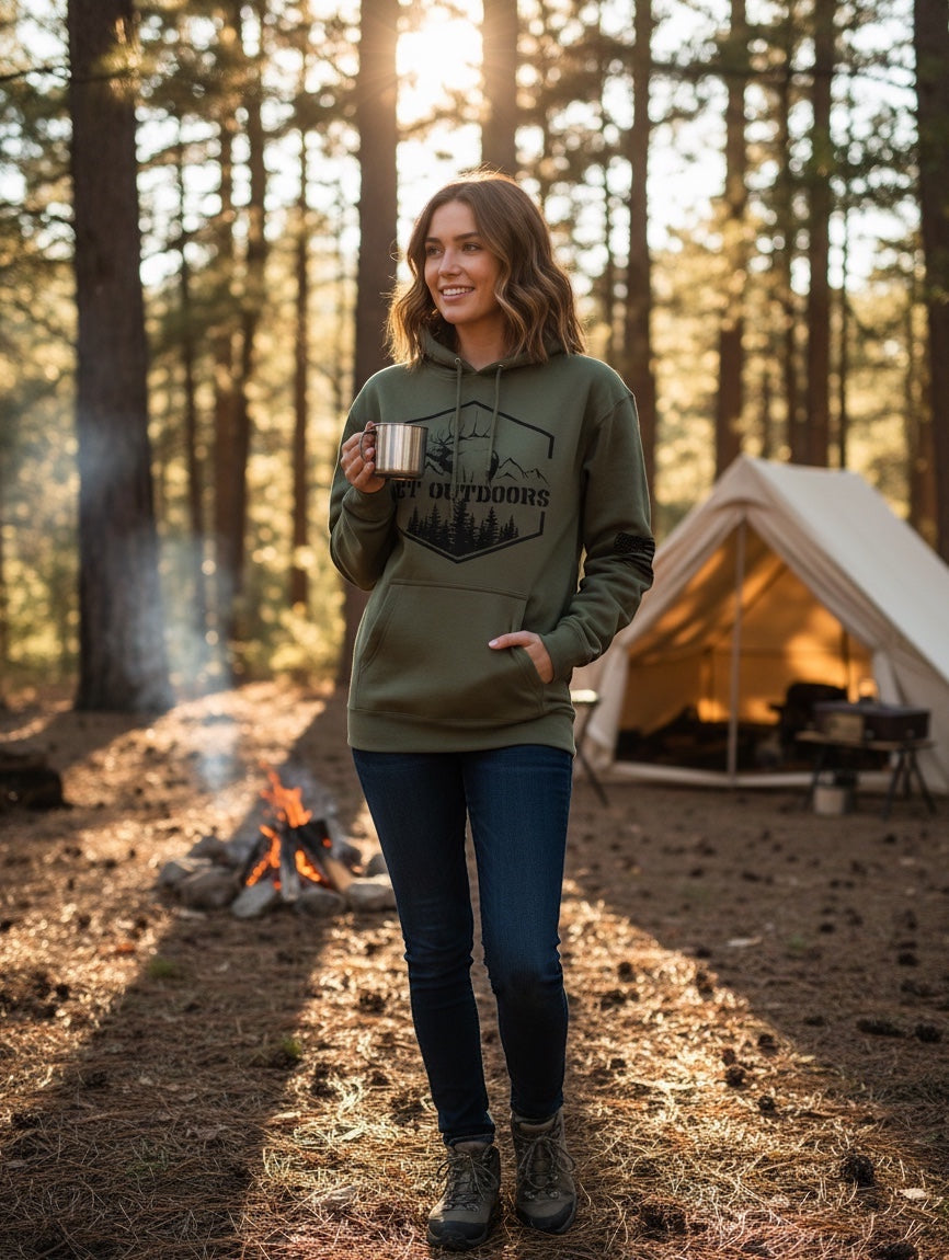 Woman wearing olive green JSD Apparel Get Outdoors Elk unisex fleece hoodie in a forest camping setting.