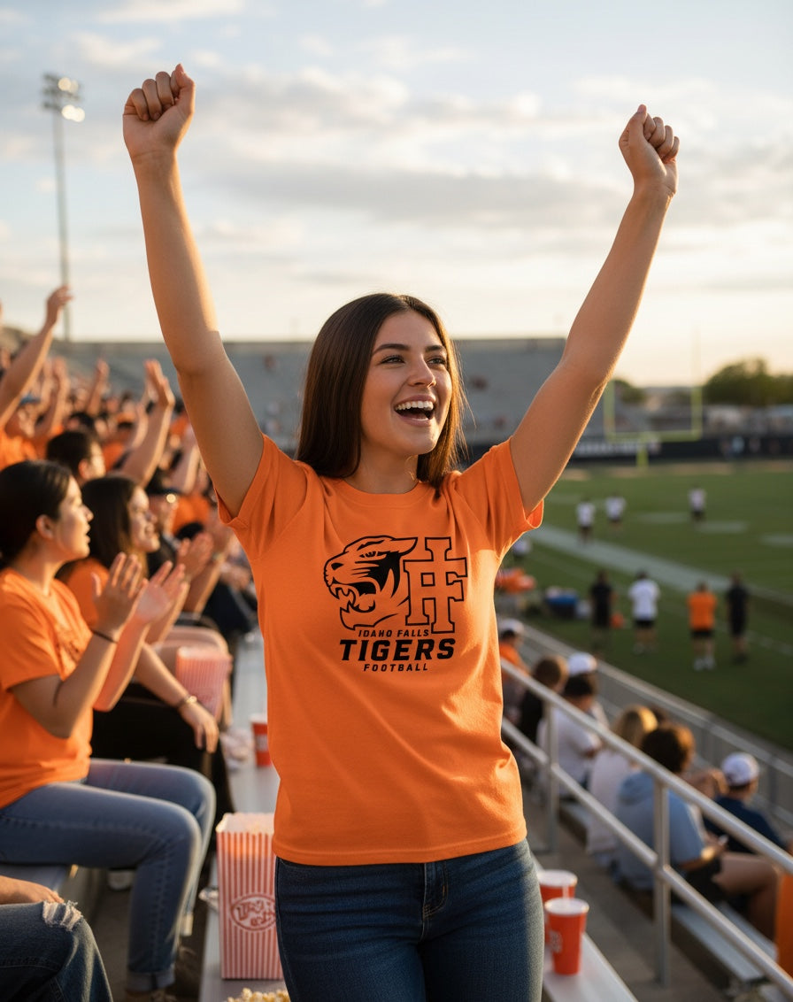 A fan wearing an orange JSD Apparel Idaho Falls Tigers Football crewneck tee while cheering in a stadium.