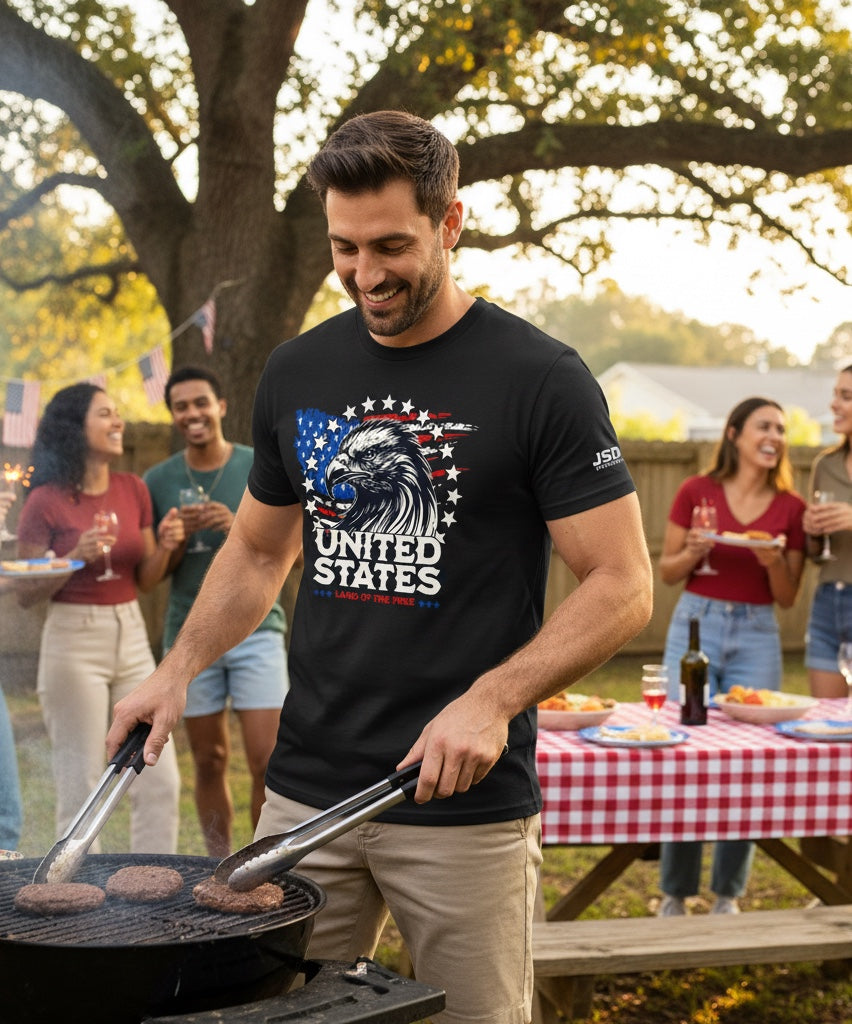 Man wearing a black JSD Apparel t-shirt with a patriotic bald eagle and American flag graphic at a backyard barbecue.