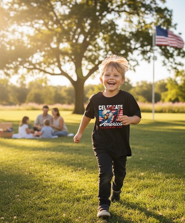 A happy young boy running in a park wearing a black JSD Apparel patriotic graphic tee with an eagle design.