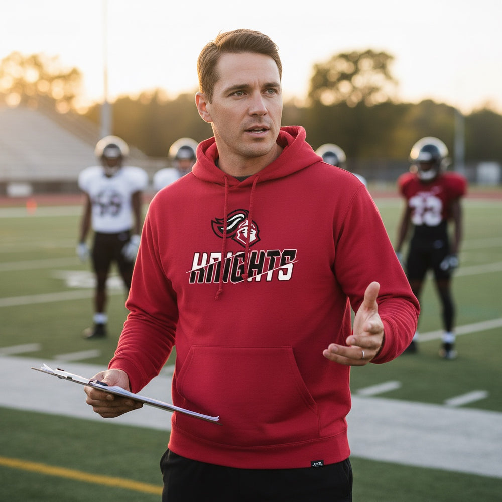 JSD Apparel red heavyweight hoodie with Hillcrest Knights graphic worn by a coach on a football field