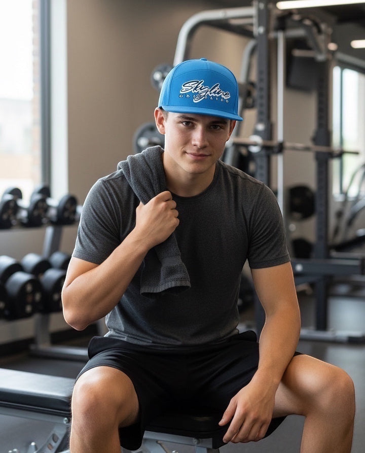 JSD Apparel Skyline Grizzlies blue performance snapback cap worn by a man in a gym setting.