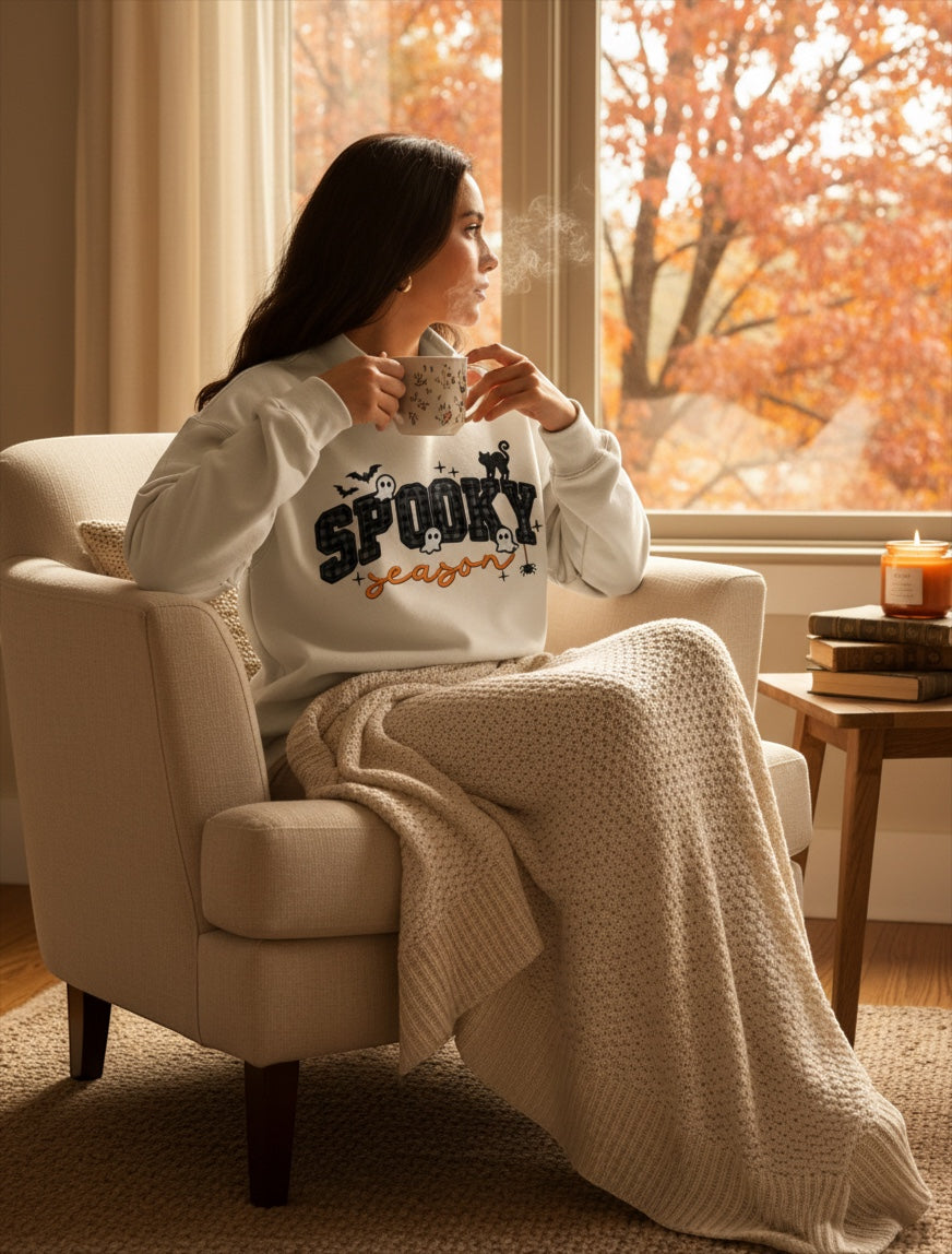 JSD Apparel Spooky Season mock neck sweatshirt with plaid lettering and Halloween graphics on a woman in a cozy chair