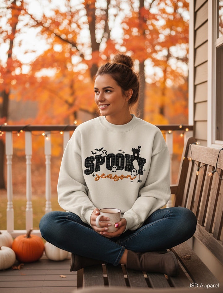 JSD Apparel Spooky Season mock neck sweatshirt with plaid lettering, ghosts, and cat print on a woman on a porch.