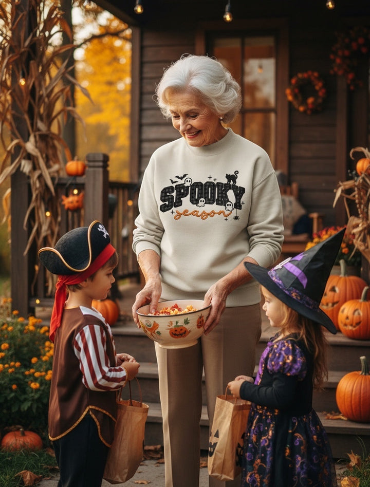 JSD Apparel Spooky Season mock neck sweatshirt worn by a woman handing candy to children in Halloween costumes