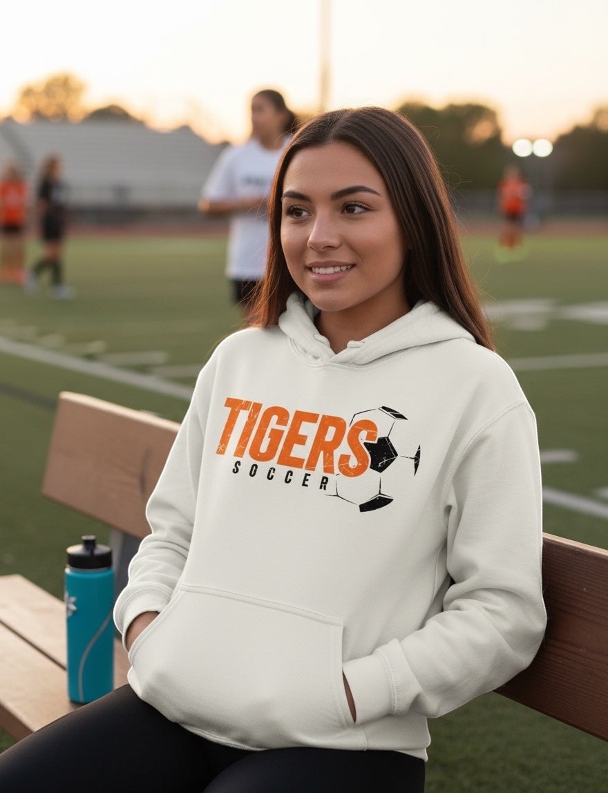 JSD Apparel Tiger Pride soccer hoodie in off-white with a distressed orange and black graphic on a female model.